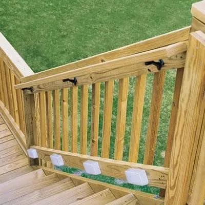 A handrail and lighting along the stairs of a wooden deck.