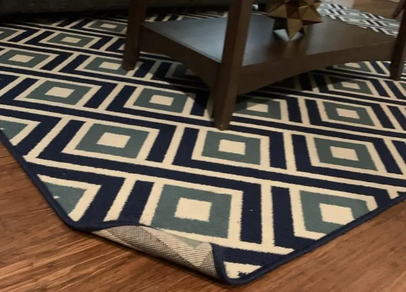 The corner of a floor rug is flipped up.