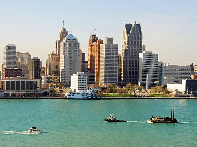 A picture of the water and boats with the Detroit Skyline in the back.