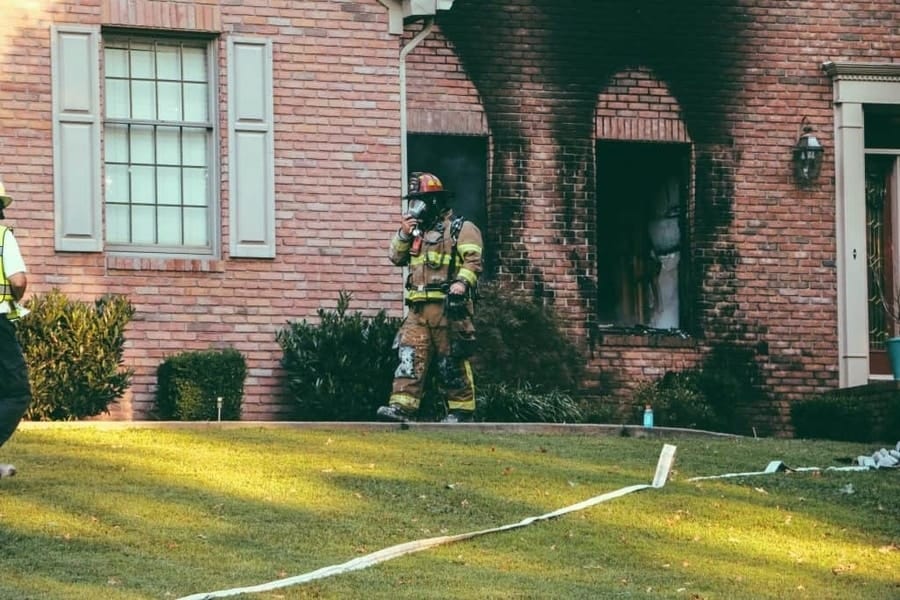 A fireman walks out of a house scorched by flames
