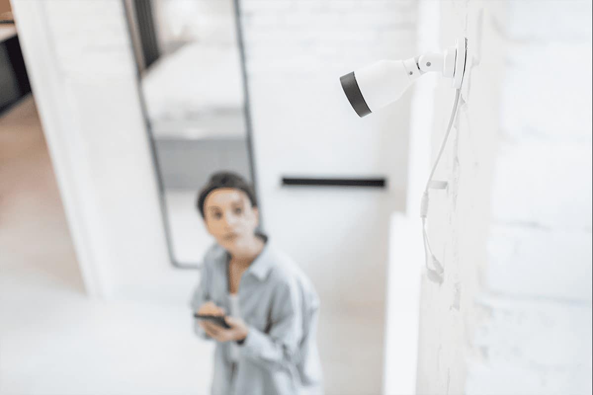 A woman looks up at a security camera on the wall