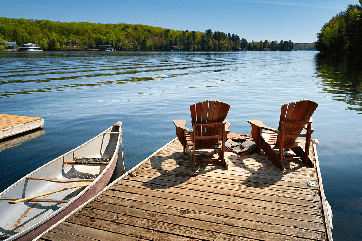 Two chairs on a dock next to a canoe