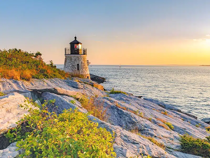 Lighthouse on the shore with a sunset over the horizon of the ocean