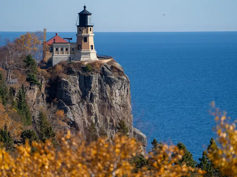 A lighthouse sits on the edge of a cliff overlooking the water in Minnesota