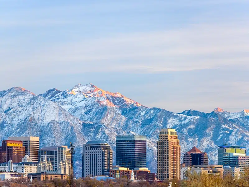 Utah city skyline in front of a scenic snowy mountain landscape 