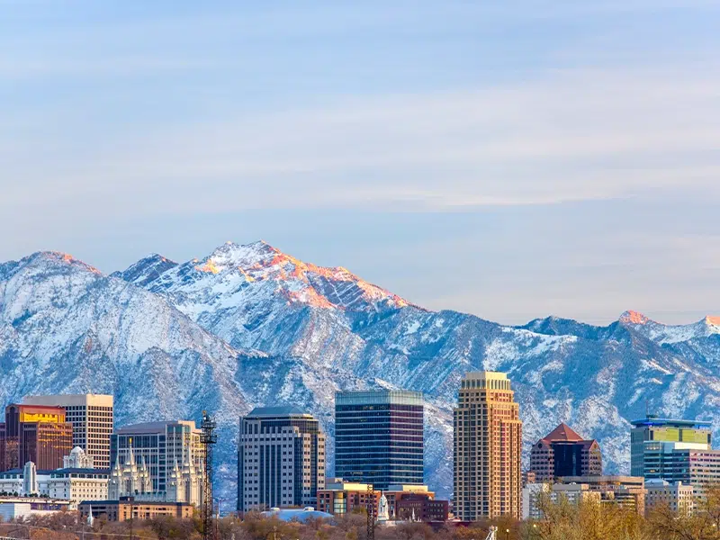 Utah city skyline in front of a scenic snowy mountain landscape